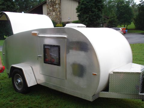 1994 Ford F-350 - A silver teardrop trailer is parked on a grassy area with a house in the background.