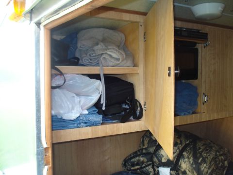 1994 Ford F-350 - Storage cabinets inside a vehicle are filled with clothing and bags, with a microwave visible in the background.