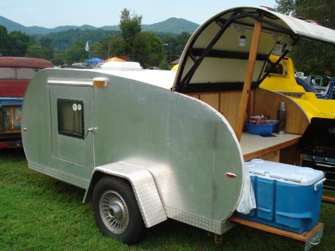 1994 Ford F-350 - This aluminum teardrop trailer features an open galley kitchen with a blue cooler and a grill, parked on grass with other vehicles in the b…