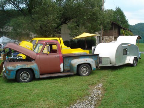 1994 Ford F-350 - This vintage Ford pickup, likely a 1955 F-100, is towing a small teardrop trailer. Another yellow truck is visible behind it.