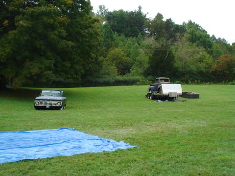 1994 Ford F-350 - A dark green 1965 Ford F-Series truck is parked on a grassy field, with another truck and trailer in the background.