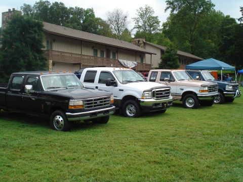 1994 Ford F-350 - Several Ford F-Series trucks are lined up on a grassy lawn in front of a lodge-like building.