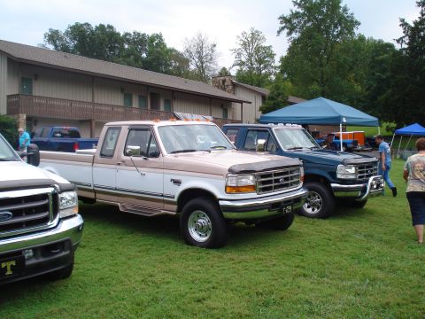 1994 Ford F-350 - A pair of Ford F-Series trucks are parked on a grassy lawn in front of a building.