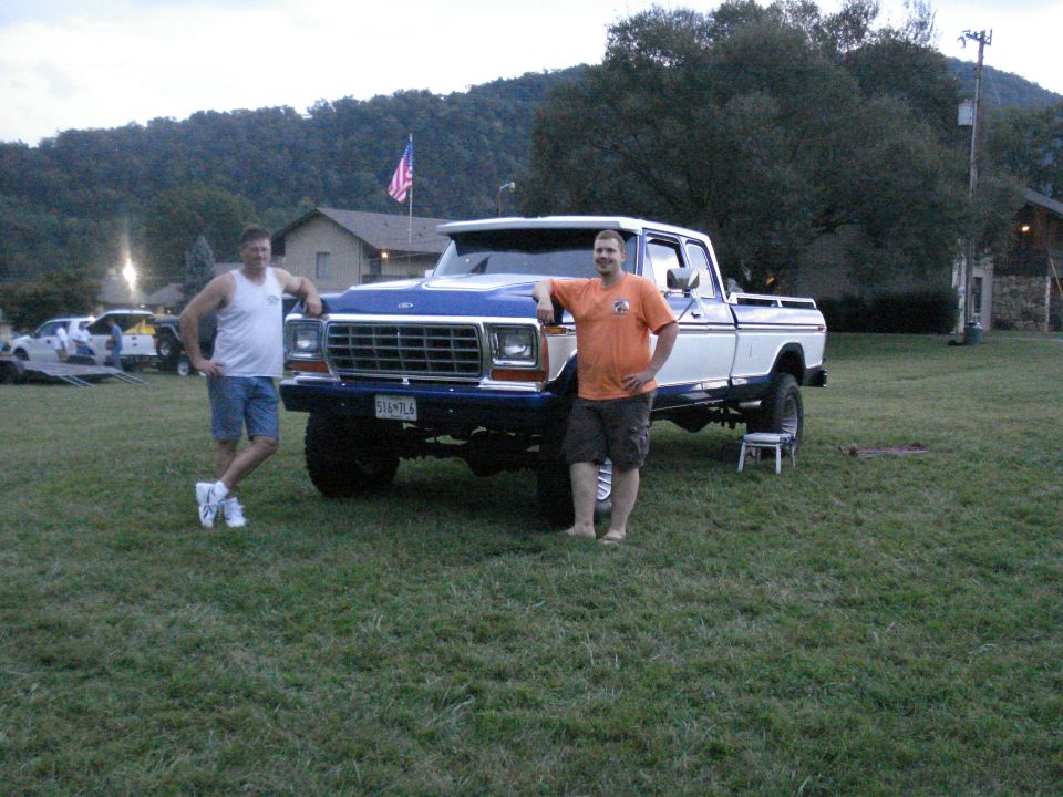 Two guys with a lifted blue and white Ford F-Series truck. Other trucks in background