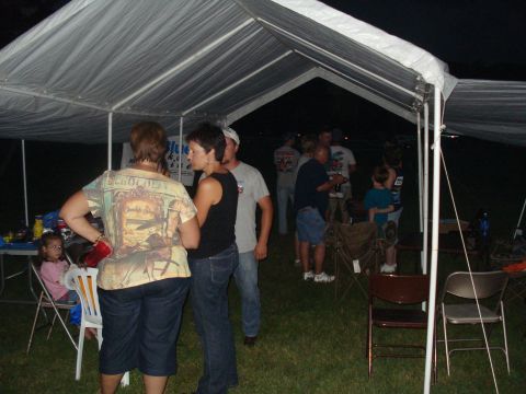 1994 Ford F-350 - An outdoor gathering takes place under a tent with several people socializing.