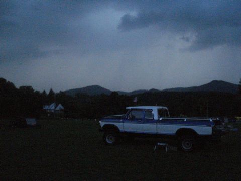 1994 Ford F-350 - A two-tone pickup truck sits in a field at dusk, with rolling hills visible behind it.