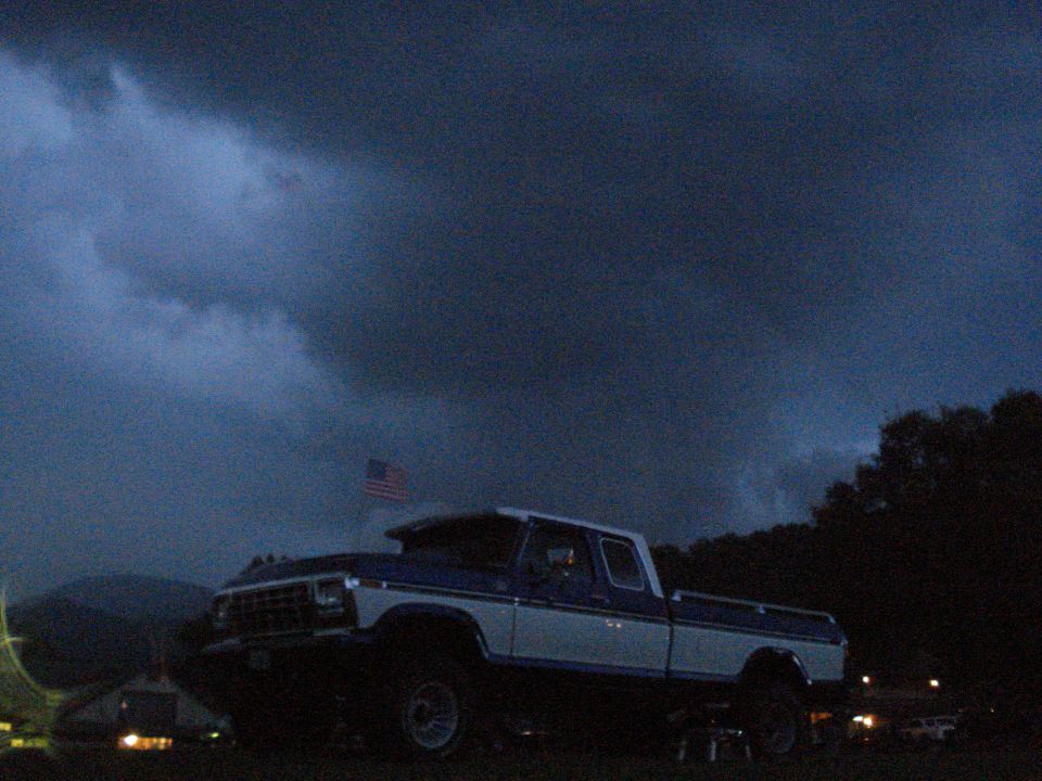 Pickup truck with an American flag in the background under a stormy sky