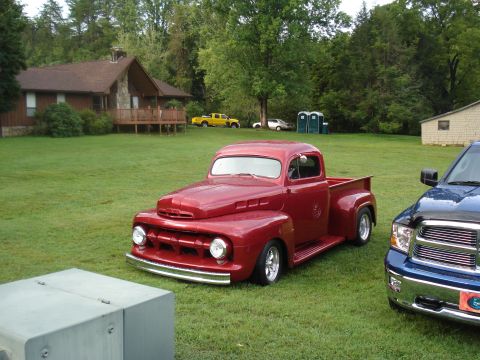 1994 Ford F-350 - A classic red pickup truck is parked on a grassy lawn next to a modern blue pickup truck.
