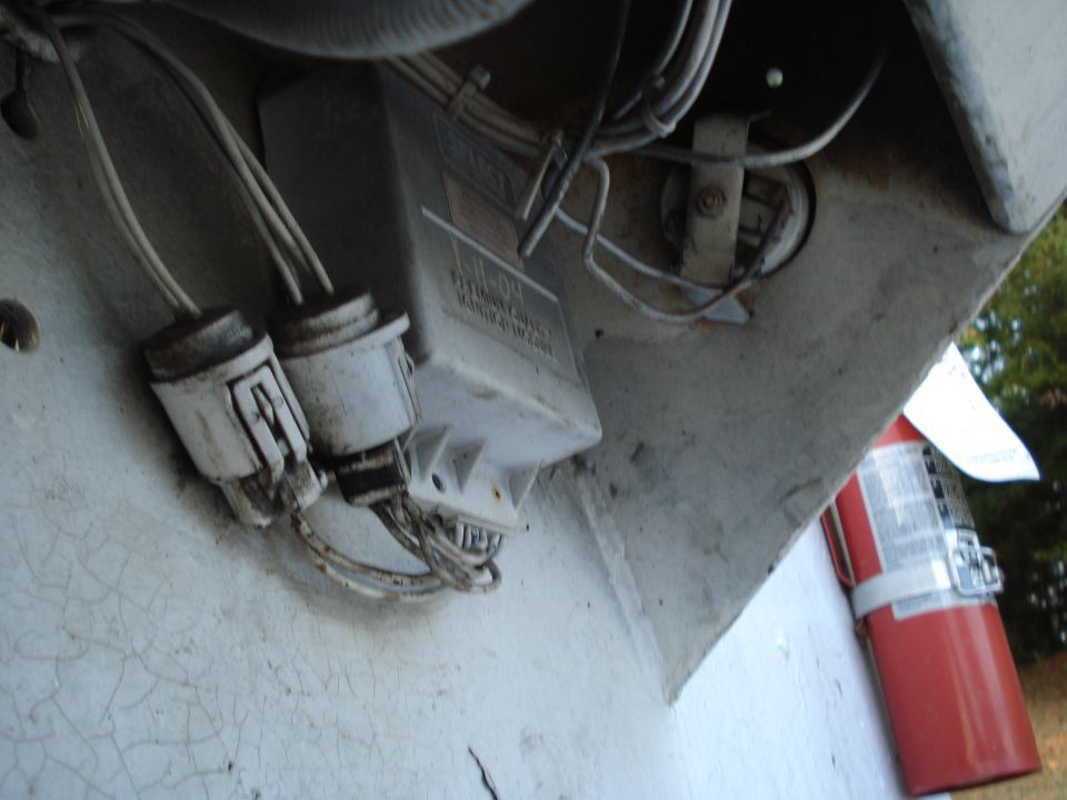 White truck undercarriage with electrical box, connectors, and red fire extinguisher