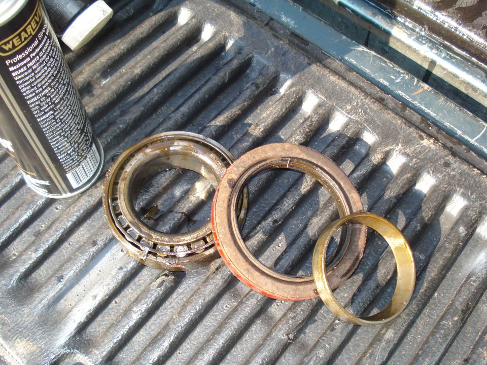 Wheel bearing and seal assembly on a truck bed, next to a can of brake cleaner