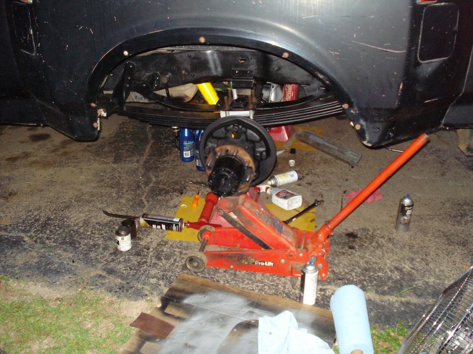 Truck rear axle is jacked up with tools and parts scattered around