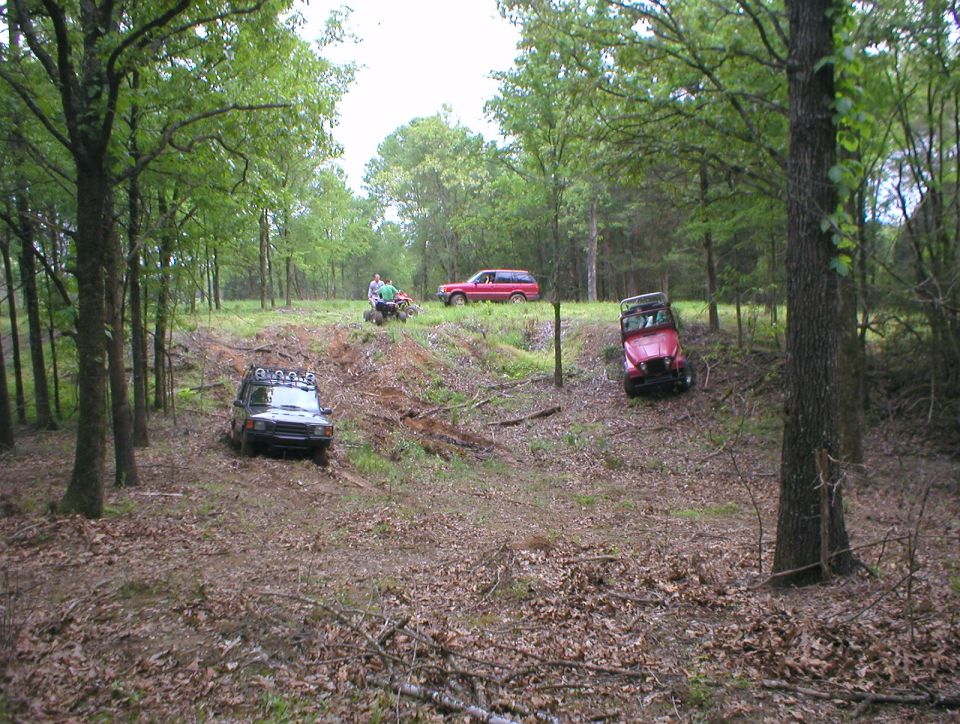 Off-road vehicles including SUVs and a Jeep on a rutted forest trail