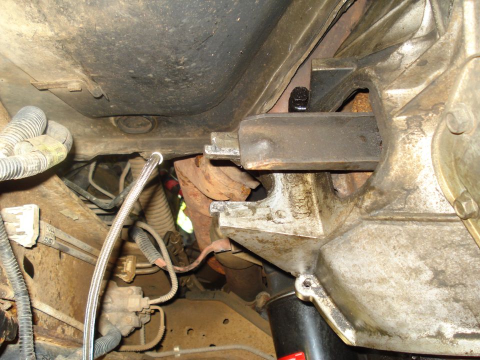 Close-up of drivetrain components with visible rust and oil