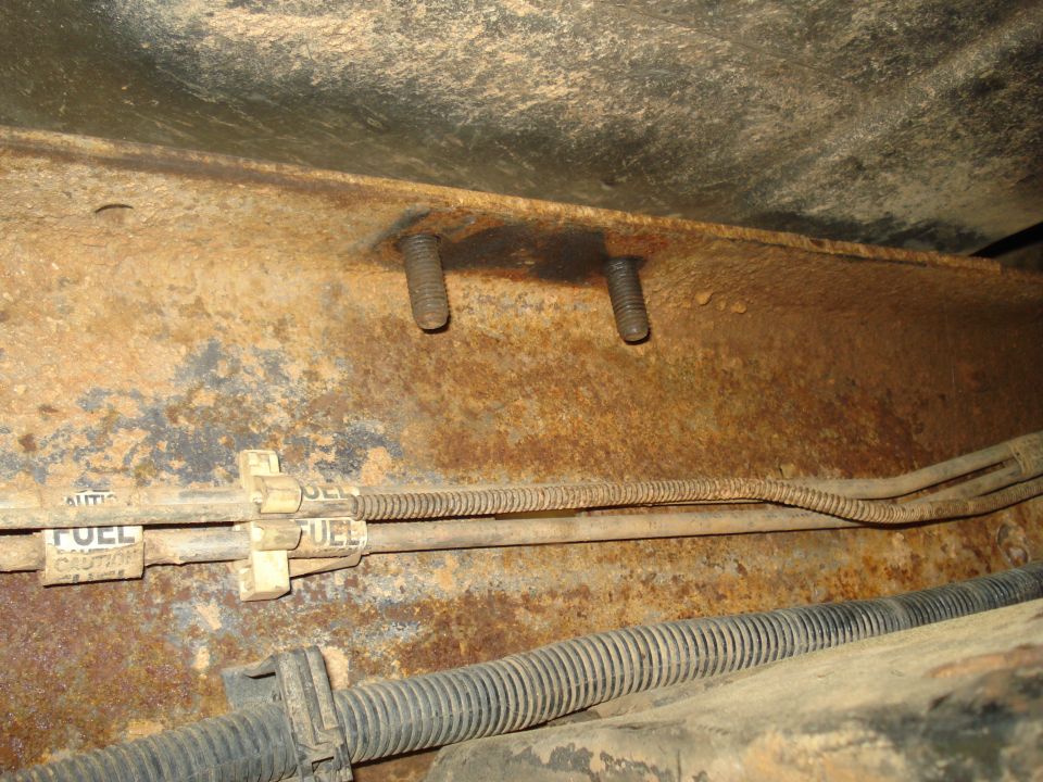 rusted truck frame with two bolts and fuel lines labeled FUEL CAUTION