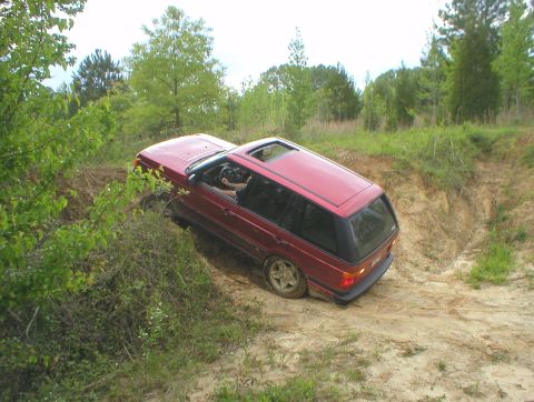 1983 Ford Bronco - A red SUV is seen navigating a challenging off-road terrain with steep dirt inclines.