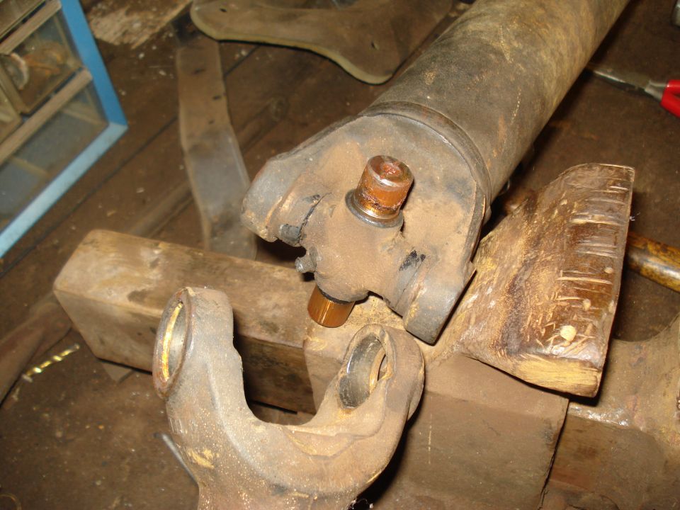 Driveshaft universal joint with copper-colored bearing caps, resting on wooden blocks