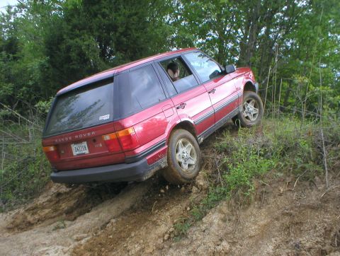 1983 Ford Bronco - Red Range Rover navigating an off-road trail on a sunny day.