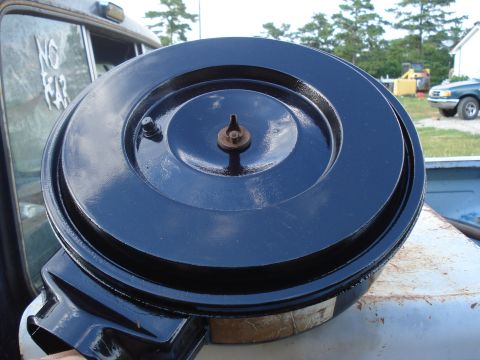 1984 Ford F-250 - A black air cleaner assembly is shown, with a bolt and nut securing the top. Another vehicle is visible in the background.