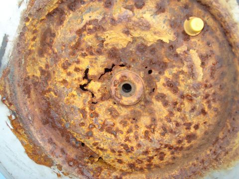 1984 Ford F-250 - This heavily corroded metal component shows significant rust damage and a small yellow cap.