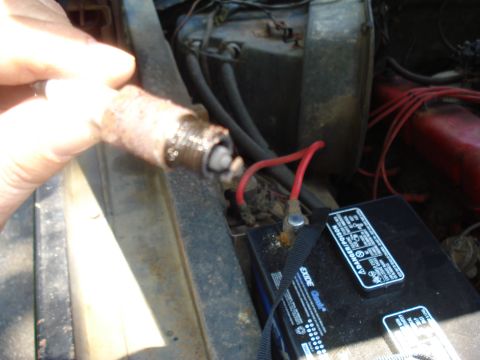 1984 Ford F-250 - A person is holding a used spark plug next to a car battery and engine bay.