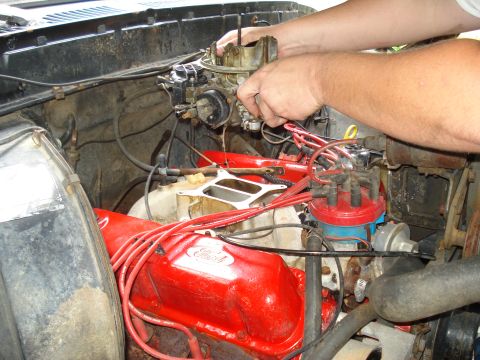 1984 Ford F-250 - Mechanic works on the carburetor of a 1977 Ford F-100 engine.