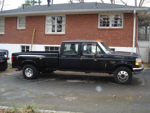 1994 Ford F-350 - A black crew cab dually pickup truck is parked in front of a brick house.