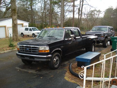 1994 Ford F-350 - A black 1994 Ford F-350 pickup truck is parked in a driveway with other vehicles visible.