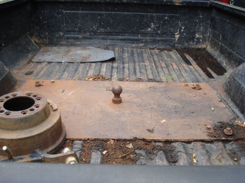 1994 Ford F-350 - The interior of a truck bed shows a fifth wheel hitch and a brake drum, with dirt and leaves scattered around.