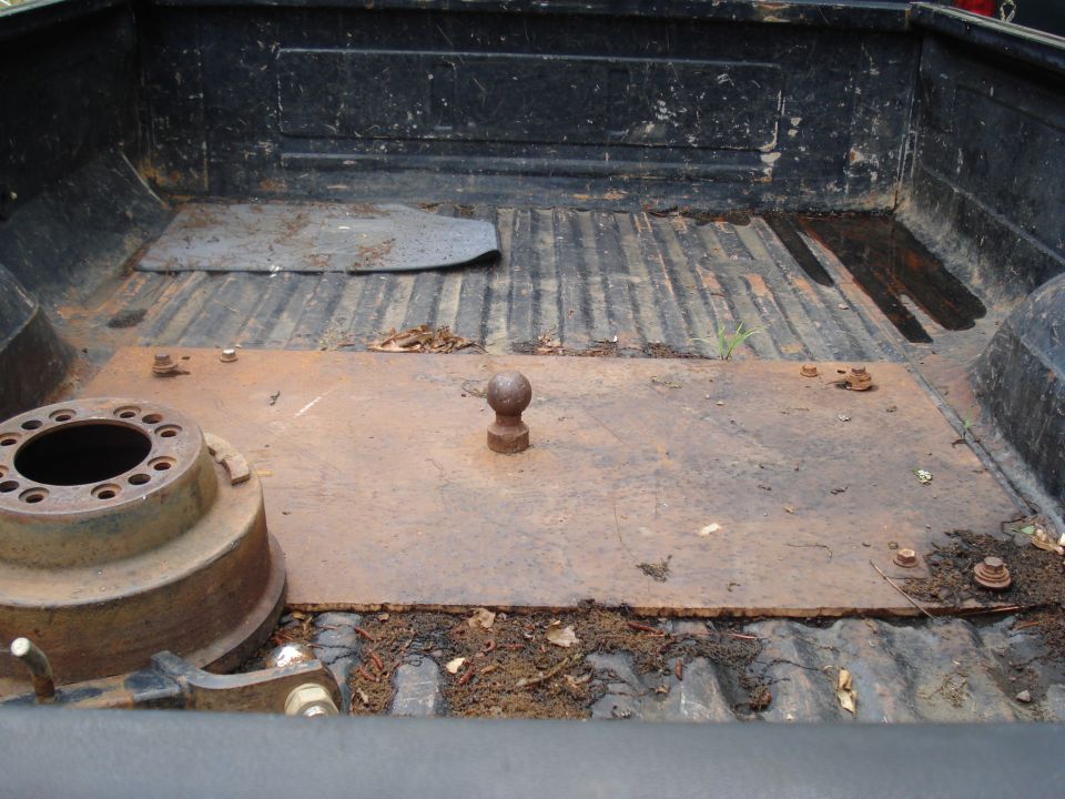 Truck bed with a fifth wheel hitch ball and a brake drum. Some debris is present