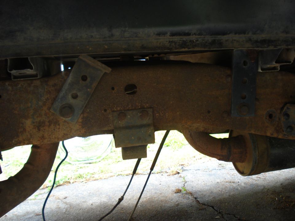 Rusty truck frame with visible suspension components and exhaust pipe