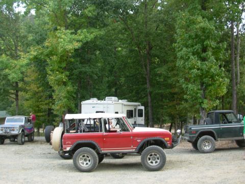 1983 Ford Bronco - Three Ford Broncos are parked outdoors near trees and RVs.