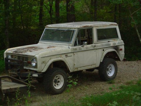 1983 Ford Bronco - This weathered Ford Bronco sits in a wooded area, showing signs of age and off-road use.