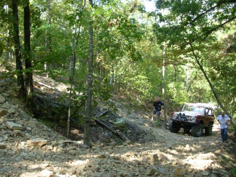 1983 Ford Bronco - This 1983 Ford Bronco navigates a challenging, rocky off-road trail surrounded by dense forest.