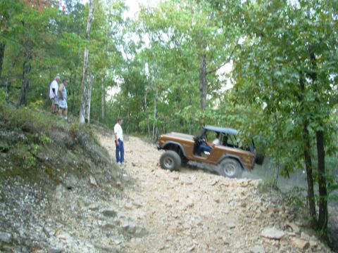 1983 Ford Bronco - Brown Ford Bronco navigates a challenging rocky terrain with its doors open.