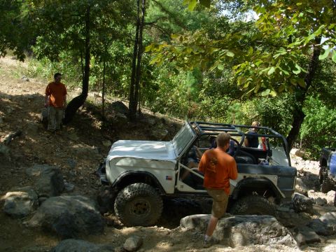 1983 Ford Bronco - This off-road SUV navigates a challenging rocky path with a roll cage installed.