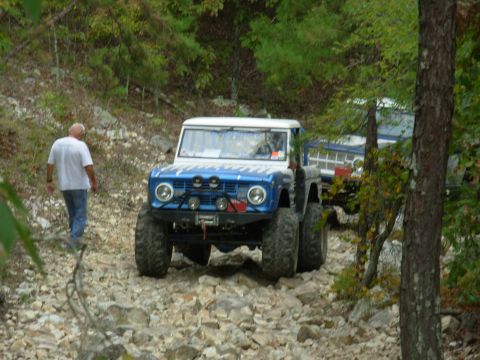 1983 Ford Bronco - A modified 1977 Ford Bronco navigates a rocky off-road trail, with another vehicle visible behind it.