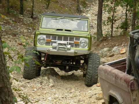 1983 Ford Bronco - A lifted green Ford Bronco navigates a rocky trail with another vehicle partially visible.