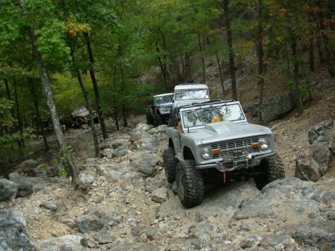 1983 Ford Bronco - Multiple off-road vehicles, including a modified Ford Bronco, traverse a challenging rocky trail.