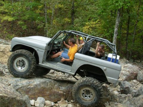 1983 Ford Bronco - This modified Bronco is tackling a challenging off-road course with multiple passengers.