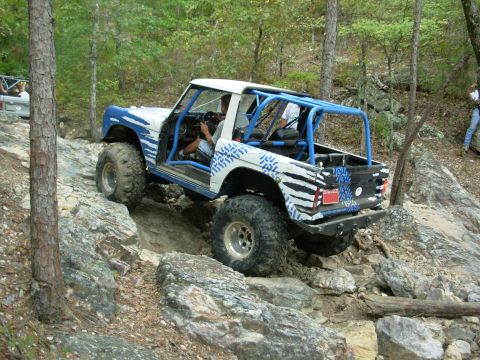 1983 Ford Bronco - This modified Ford Bronco navigates a rocky trail with a blue roll cage and custom paint.
