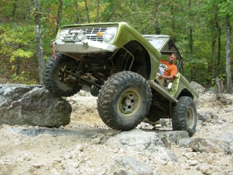 1983 Ford Bronco - Off-road vehicle navigating a rocky trail with significant suspension articulation.