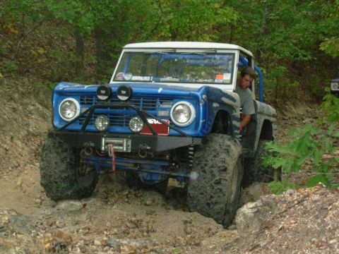 1983 Ford Bronco - A modified first-generation Ford Bronco navigates a rocky, wooded trail.