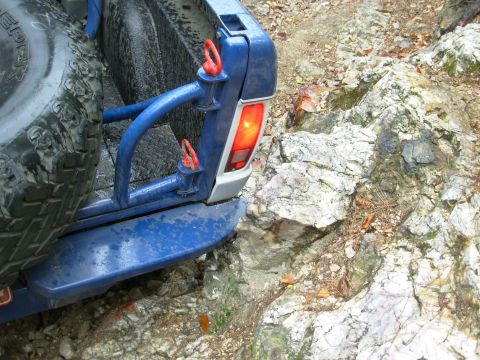 1983 Ford Bronco - The vehicle's rear is angled towards a rocky incline, with its taillight illuminated.