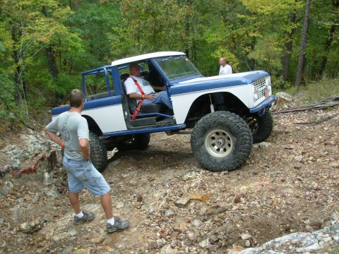 1983 Ford Bronco - Modified Ford Bronco with large tires and roll cage on a rocky trail.