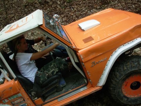 1983 Ford Bronco - The interior of an orange 1983 Ford Bronco is visible as two people navigate off-road terrain.