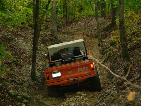 1983 Ford Bronco - This classic Ford Bronco navigates a steep, wooded path, its off-road capabilities.