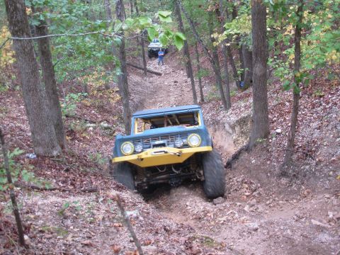 1983 Ford Bronco - This modified SUV navigates a challenging off-road course through a dense forest.