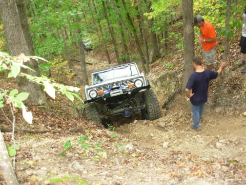 1983 Ford Bronco - Two Ford Broncos navigate a challenging off-road trail with spectators.