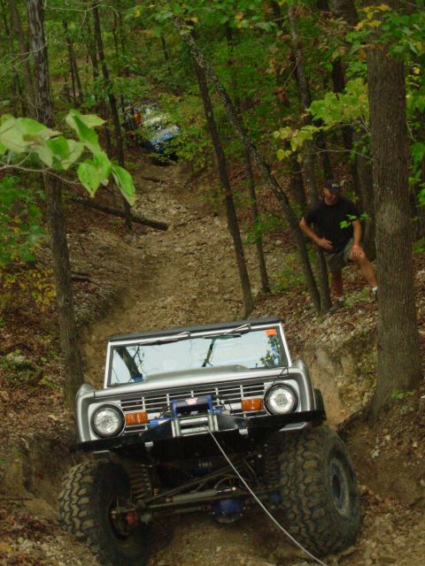 1983 Ford Bronco - A modified Ford Bronco navigates a challenging off-road trail with another vehicle in the background.