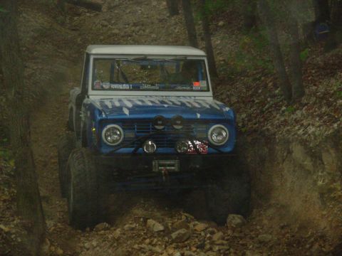 1983 Ford Bronco - This modified Ford Bronco navigates a rocky, wooded trail with a prominent winch and auxiliary lights.